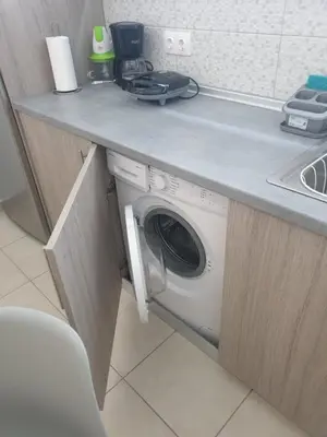 a washing machine under a counter in a kitchen at green - comfy center rodos in Asgourou