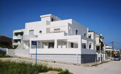 a large white building with a car in front of it at green - comfy center rodos in Asgourou