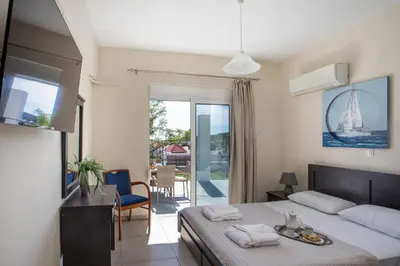 a bedroom with a bed and a table and a balcony at Sunny Villa in Faliraki