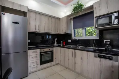 a kitchen with wooden cabinets and a stainless steel refrigerator at Sunny Villa in Faliraki