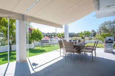 a patio with a table and chairs under a white canopy at Sunny Villa in Faliraki