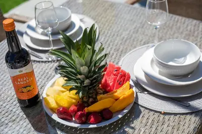 a plate of fruit on a table with a bottle of wine at Sunny Villa in Faliraki