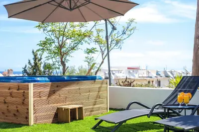 a patio with a hot tub and an umbrella at Sunny Villa in Faliraki