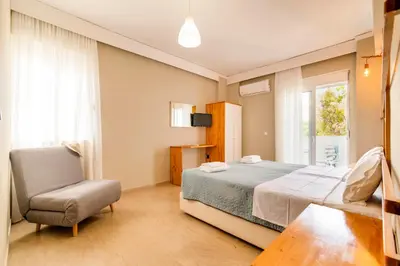 a bedroom with a bed and a chair and a window at Lefka Hotel & Apartments in Rhodes Town