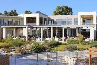 a large white building with people sitting at tables at Port Royal Villas and Spa - Adults Only in Kolimbia