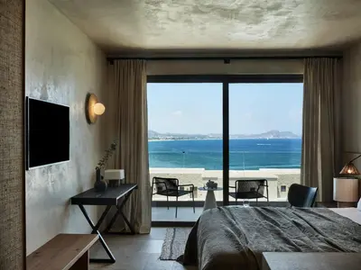 a bedroom with a bed and a view of the ocean at Port Royal Villas and Spa - Adults Only in Kolimbia