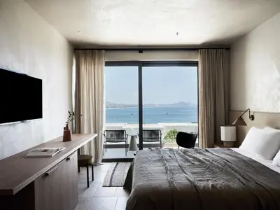 a hotel room with a bed and a view of the ocean at Port Royal Villas and Spa - Adults Only in Kolimbia