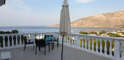 an umbrella on a balcony with a view of the ocean at Nikos studios in Livadia