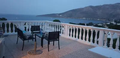a balcony with three chairs and a table with a view at Nikos studios in Livadia