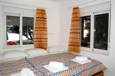 a bed in a room with two windows at Marina Beach House in Lardos