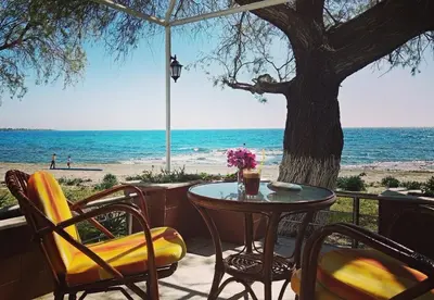 a table and chairs on a patio with the beach at Marina Beach House in Lardos