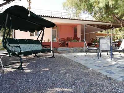 a swing with chairs and an umbrella in a yard at Marina Beach House in Lardos