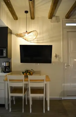 a kitchen with a table with chairs and a tv on the wall at Haraki Blue Pearl Luxury studio in Haraki