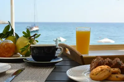 a table with a cup of coffee and a glass of orange juice at Haraki Blue Pearl Luxury studio in Haraki