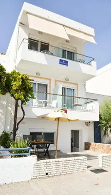 a white building with an umbrella and a table at Haraki Blue Pearl Luxury studio in Haraki