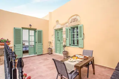 a dining room with green shutters and a table and chairs at Traditional Stonehouse In Kalithies Village in Kalithies