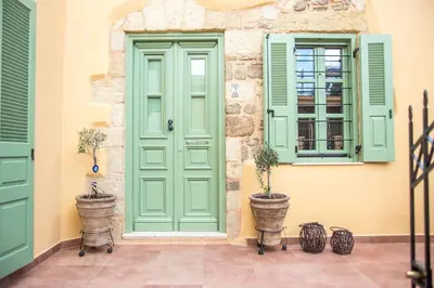 a green door and windows on a building with potted plants at Traditional Stonehouse In Kalithies Village in Kalithies