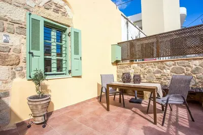 a patio with a table and chairs and a window at Traditional Stonehouse In Kalithies Village in Kalithies