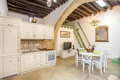 a kitchen with white cabinets and a table with chairs at Traditional Stonehouse In Kalithies Village in Kalithies