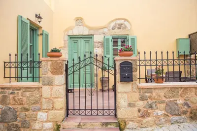 a gate to a house with green doors and windows at Traditional Stonehouse In Kalithies Village in Kalithies