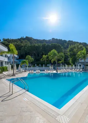 a large swimming pool with chairs and trees at Oceanis Park Hotel in Ixia