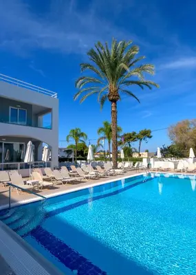 a swimming pool with chairs and a palm tree at Oceanis Park Hotel in Ixia