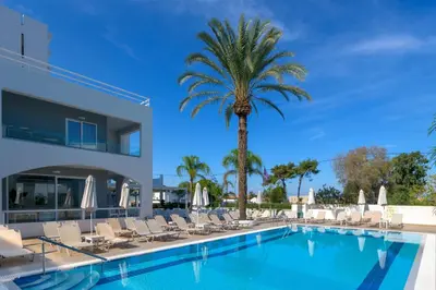 a swimming pool with chairs and a palm tree at Oceanis Park Hotel in Ixia