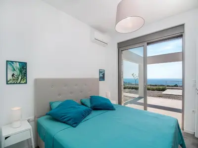 a bedroom with a blue bed with a view of the ocean at Villa in Rhodes near Ladiko Bay in Kalithies