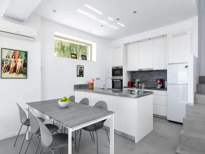 a kitchen with white cabinets and a table and chairs at Villa in Rhodes near Ladiko Bay in Kalithies