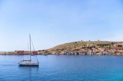 a boat in the water with a small island at Admiral's House in Halki