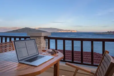 a laptop computer sitting on a wooden table on a balcony at Admiral's House in Halki