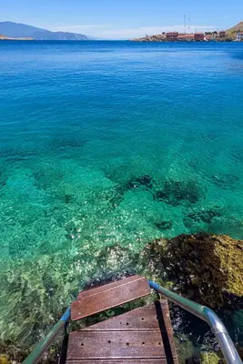 a wooden boat in the water near the shore at Admiral's House in Halki