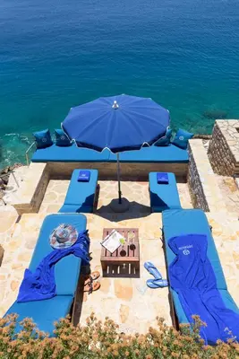 a group of blue chairs and an umbrella next to the ocean at Admiral's House in Halki