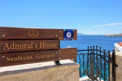 a wooden bench sitting on top of a balcony with the ocean at Admiral's House in Halki