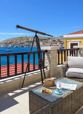 a table on a balcony with a view of the water at Admiral's House in Halki