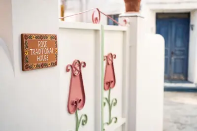 a sign on a white fence with flowers on it at Rose traditional house in Archangelos