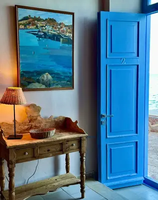 a room with a blue door and a table with a lamp at Villa Hiona-Seafront Villa in Halki