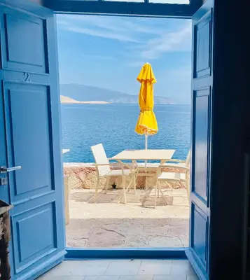 an open door with a table and a yellow umbrella at Villa Hiona-Seafront Villa in Halki