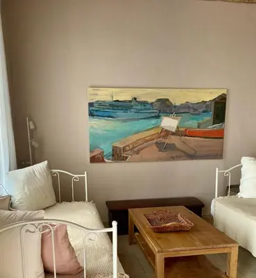 a living room with a table and a painting on the wall at Villa Hiona-Seafront Villa in Halki
