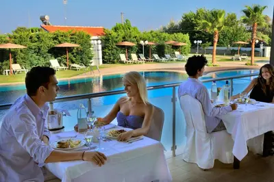 a group of people sitting at tables in front of a pool at Afandou Bay Resort Suites in Afantou