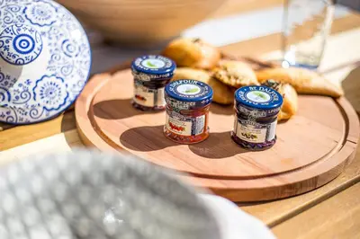 a table with three jars of jam and a plate of food at Euphoria Luxury apartment in Faliraki