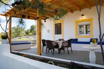 a patio with a table and chairs under a pergola at Vista Mare in Archangelos