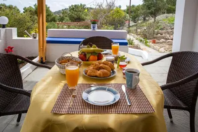a table with a plate of food and orange juice at Vista Mare in Archangelos
