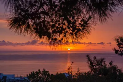 a sunset over the ocean with the sun in the sky at Vista Mare in Archangelos