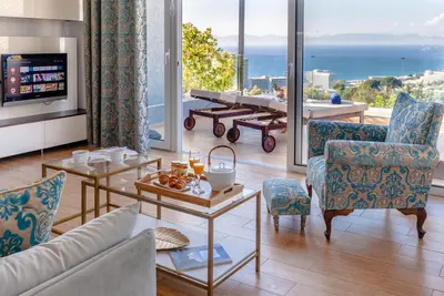 a living room with a view of the ocean at FlyViewFlatsBLUE PrivateHotTub with SeaView in Rhodes Town