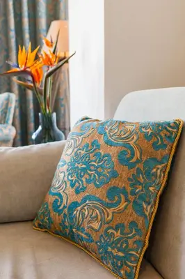 a pillow on a couch with a vase of flowers at FlyViewFlatsBLUE PrivateHotTub with SeaView in Rhodes Town