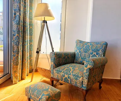 a chair and a lamp in a room with a window at FlyViewFlatsBLUE PrivateHotTub with SeaView in Rhodes Town