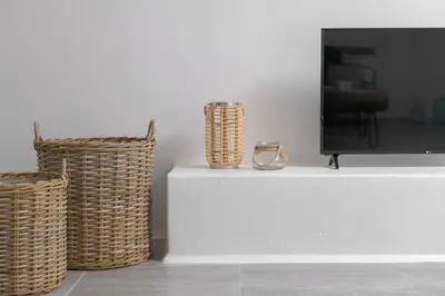 a tv sitting on a white table with two baskets at Mea Terra Villas in Lachania