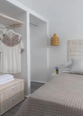 a white bedroom with a bed and a dresser at Mea Terra Villas in Lachania