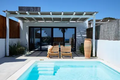 a swimming pool with two chairs and a pergola at Mea Terra Villas in Lachania